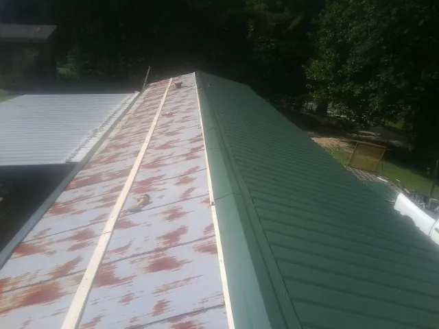 Old rusted panels beside newly installed green metal roofing — Wind Damage Roof Repair by Roofing Brothers in East Galesburg