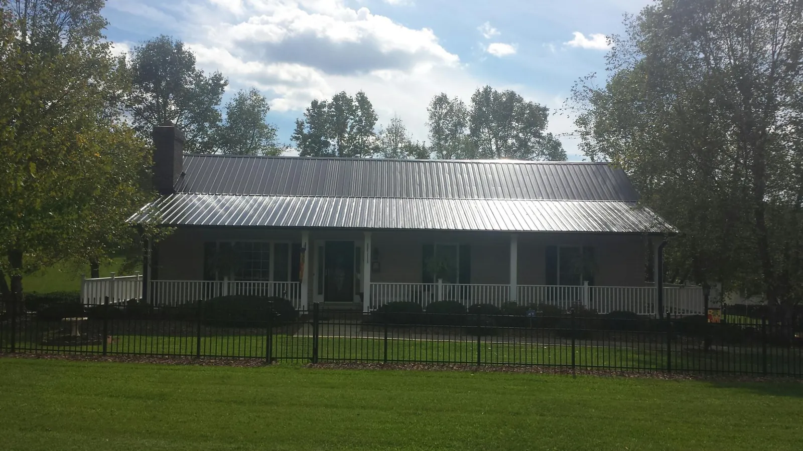 Gray metal roof on a brick ranch with a full width front porch — Gutter Guard Installation work by our crew in East Galesburg