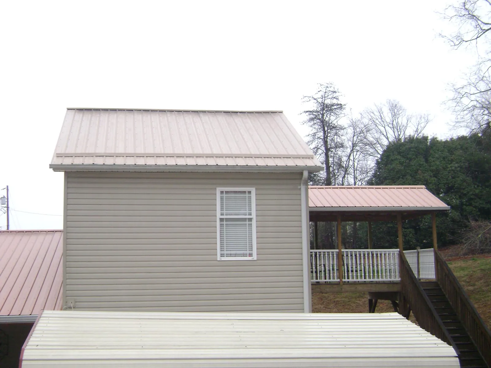 Tan metal roofs on a two story addition and attached porch, from a Roof Replacement job in East Galesburg
