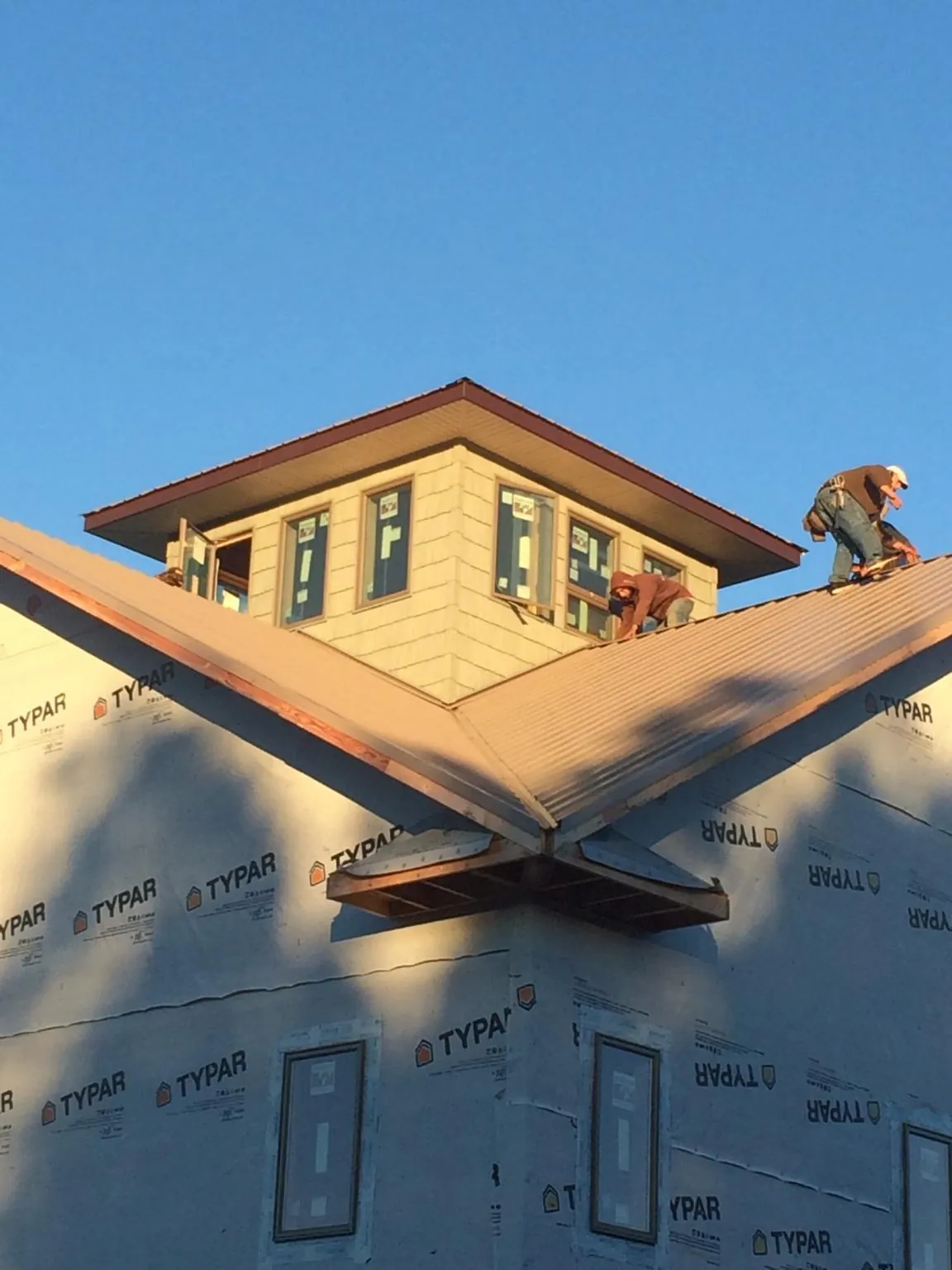 Roofers working around a rooftop cupola on a new metal roof at sunset — Roof Waterproofing in East Galesburg by Roofing Brothers